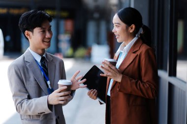 Başarılı genç iş adamları modern iş binası önünde konuşuyor, birlikte çalışıyorlar.