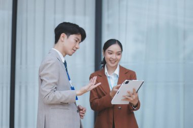 Başarılı genç iş adamları modern iş binası önünde konuşuyor, birlikte çalışıyorlar.