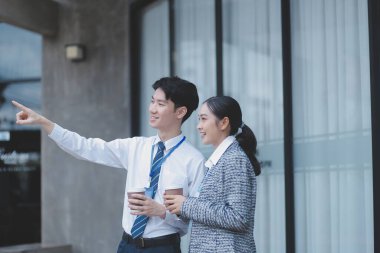 Ofisteki iş arkadaşları ofis binasının dışında yeni projeleri tartışıyor, dijital tablet tutuyorlar. Ofis binalarının önünde duran iki iş arkadaşı iş planını tartışıyor.