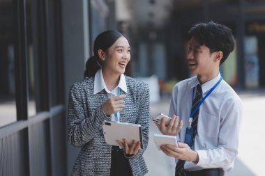 Ofisteki iş arkadaşları ofis binasının dışında yeni projeleri tartışıyor, dijital tablet tutuyorlar. Ofis binalarının önünde duran iki iş arkadaşı iş planını tartışıyor.