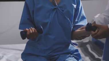 Doktor üniformalı hasta elini tutuyor.