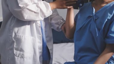 Genç bayan doktor el ele tutuşuyor. Hastane koğuşunda doktor eli hasta veriyor. Hastane koğuşu kavramı.