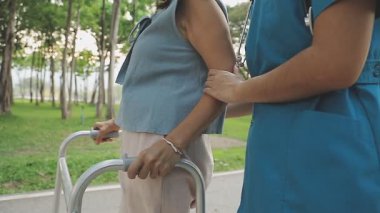 Parkta eli tekerlekli sandalyede olan kadın.