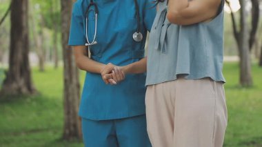 Parkta dikilmiş konuşan iki genç Asyalı kadın doktor..