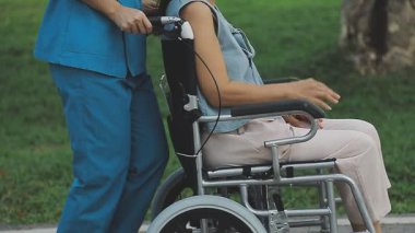 Parkta tekerlekli sandalyesi olan genç bir kadın.