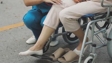 Tekerlekli sandalyedeki engelli kadın ayağını tutuyor.