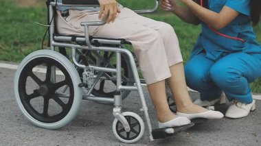 Hastanedeki hastayla birlikte tekerlekli sandalyedeki Asyalı hemşire.