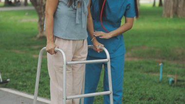 Genç hemşire hastasıyla yürüyor.