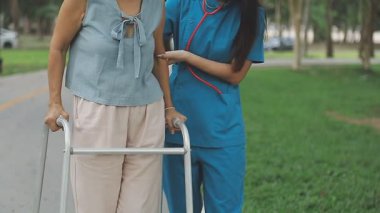 Kıdemli Asyalı kadın ve hemşiresi parkta yürüyorlar..