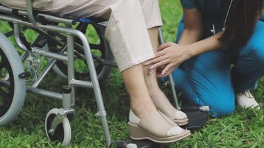 Hemşiresiyle birlikte parkta yürüyen Asyalı kadın..