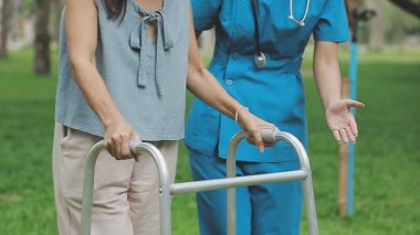 Hemşire hastaya tekerlekli sandalyede yürümesi için yardım ediyor