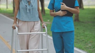 Genç Asyalı kadın hasta parkta tekerlekli sandalyede yürüyor..
