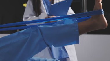 Hastanede steteskoplu mavi üniformalı ve tıbbi maskeli genç bir kadın var.