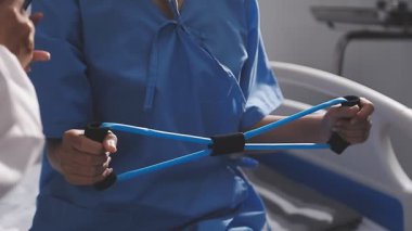 Doktor rehabilitasyon merkezinde bir hastayla rehabilitasyon terapisi yapıyor..