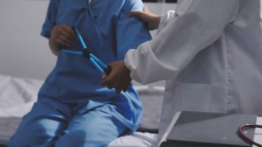 Erkek doktor hastane koğuşundaki hastayı muayene ediyor.