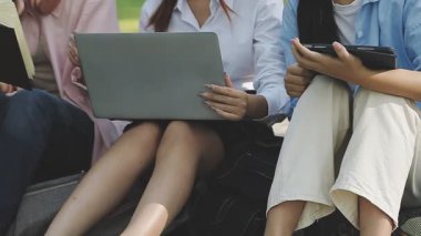 Genç kadınlar bankta oturuyor ve dizüstü bilgisayar kullanıyorlar..