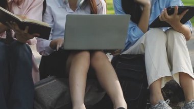 Kampüste dizüstü bilgisayarı ve kitapları olan öğrenciler