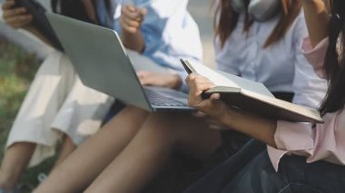 Öğrenciler bir bankta oturuyor, bir üniversite kampüsünde okuyor.