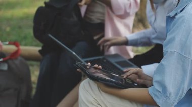 Parkta dizüstü bilgisayar kullanan genç kadın.