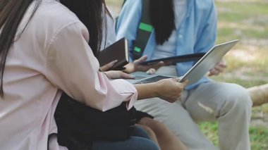 Genç Asyalı kadınlar çimlerin üzerinde tablet ve tablet kullanıyorlar.