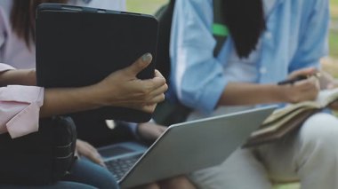 Parkta elinde tablet ve defter olan bir grup insan.