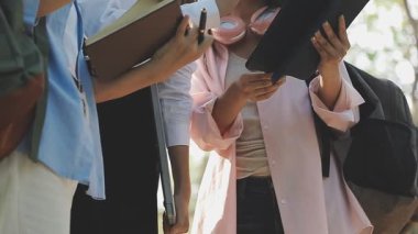 Asyalı kız öğrenci el ele tutuşup kitap okuyor.