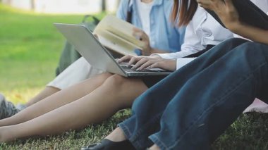 Gençler dizüstü bilgisayar kullanıyor ve birlikte parkta, iş ve eğitim kavramında okuyorlar.