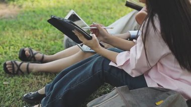 Kadınlar dizüstü bilgisayarlarda çalışıyor ve çimlerin üzerinde oturuyorlar..