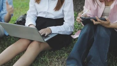 İş kadınları dizüstü bilgisayarla çalışıyor ve parkta oturuyor..