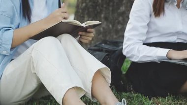 Bayan öğrenciler parkta ders çalışıyor.