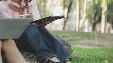 İki kız dışarıda otururken dizüstü bilgisayar kullanıyor..