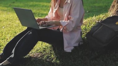 Genç kız öğrenci parkta dizüstü bilgisayarla çalışıyor.