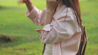 Parkta akıllı telefon kullanan genç bir kadın.