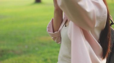 Kadınlar, yeşil çimen arka planında beyaz kese kağıdını tutuyorlar, yumuşak odaklı.