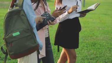 Genç Asyalı kadın kitap okuyor ve parkta gülümsüyor.