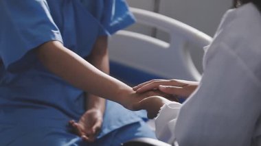 Genç bayan doktor hasta kollarını tutuyor.