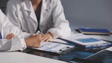 Doktor ve hasta masada otururken bir şey tartışıyorlar.