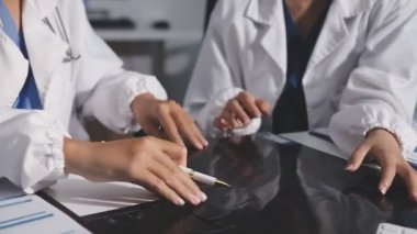 Beyaz önlüklü ve steteskoplu iki kadın doktor klinikteki masada bir tablet bilgisayarı tartışıp kullanıyorlar. tıbbi sigorta kavramı