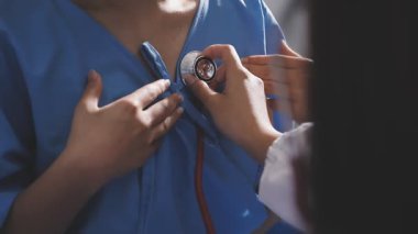 Üniformalı kadın doktor hastaların kalbini steteskopla muayene ediyor.