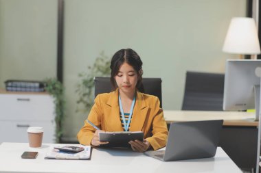 Modern ofis odasında dizüstü bilgisayarla projesinde çalışan çekici genç bir iş kadını..