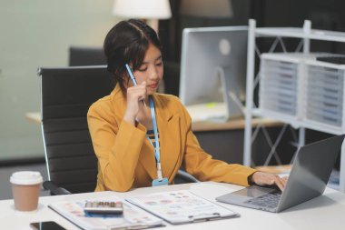 Modern ofis odasında dizüstü bilgisayarla projesinde çalışan çekici genç bir iş kadını..