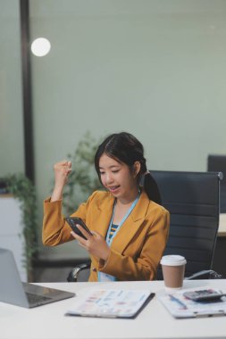 Asyalı iş kadını dizüstü bilgisayar kullanıyor ve ofiste hesap makinesi ile çalışıyor, mali raporu, iş planı yatırımını, mali analiz konseptini analiz etmeyi planlıyor..