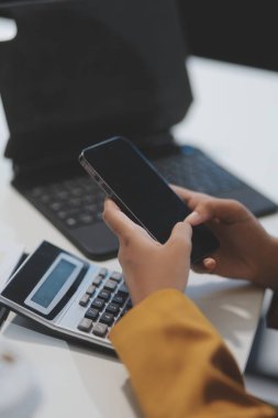 Ofisteki resmi takım elbiseli Asyalı iş kadını akıllı telefon ve çalışma süresince mutlu ve neşeli.