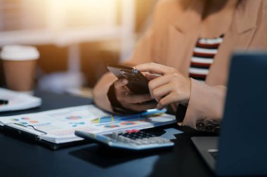 Ofiste çalışırken elinde akıllı telefon tutan Asyalı güzel bir iş kadını..