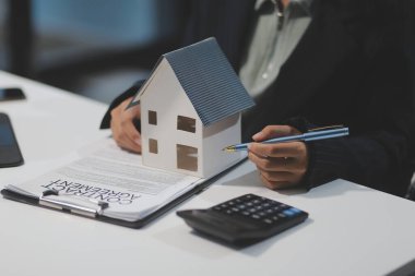 Real estate agents explain models of housing estates in projects to elaborate to clients, explaining and presenting information about homes and purchasing loans. Real estate trading concept.