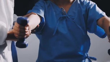 Doktor spor salonunda dambıllarla egzersiz yapıyor.