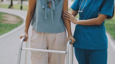 Kadın hemşire hastaya hastanede tekerlekli sandalyede yardım ediyor.