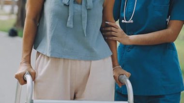 Evde tekerlekli sandalyesi olan genç Asyalı hemşire ve hasta..