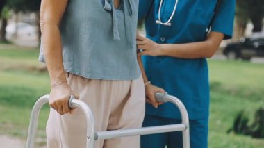 Tekerlekli sandalyeli bir kadın parkta yürüyor