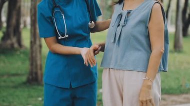 Kadın hemşire ve doktor parkta dikilip hastalarına elini uzatıyor. sağlık ve bakım.